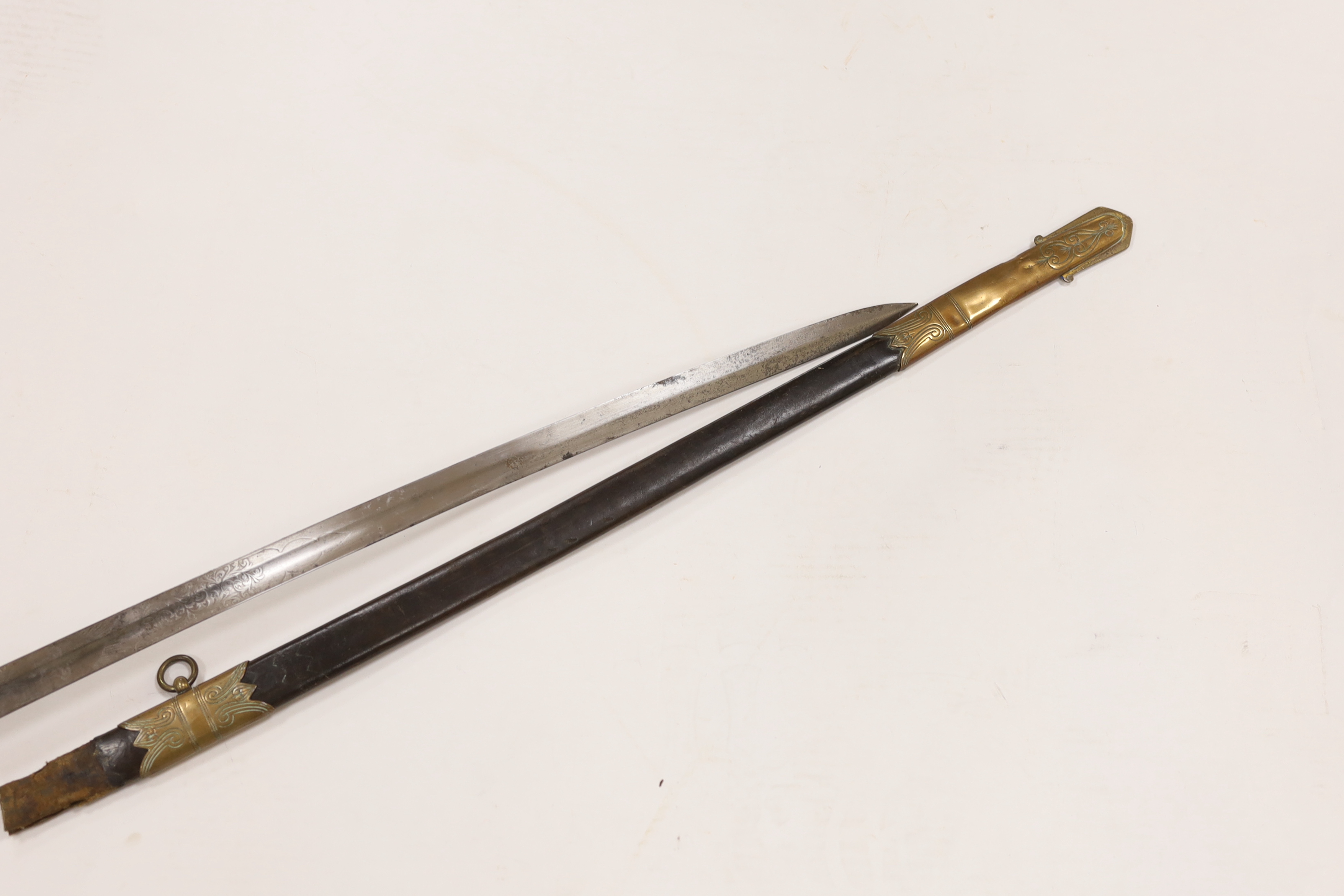 A late Victorian naval officer’s sword with regulation brass hilt, lion head pommel and blade etched with crown, VR and fouled anchor in its leather scabbard, top mount missing, blade 77cm